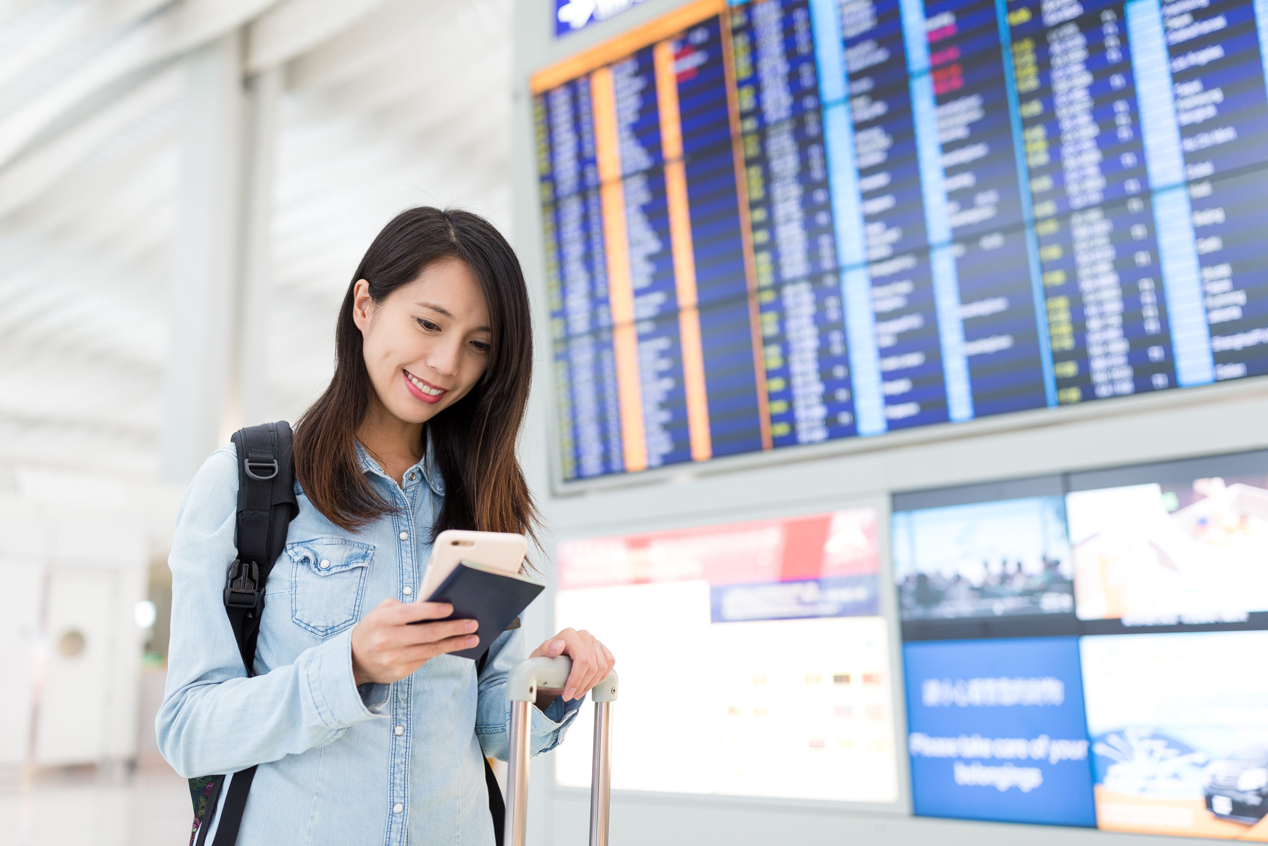 young woman using cellphone in airport KE9NFAM scaled